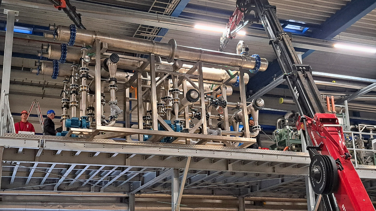 De skid met warmtewisselaars, leidingwerk en pompen staat op een bordes, hoog in de fabriek van Cirec.